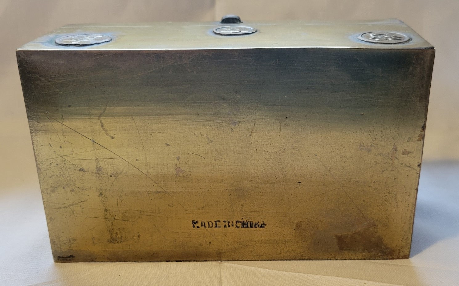 Antique brass box curio made in China, with a domed lid. The interior bottom has wood inserts on three side (one side is missing). The exterior has welded medallions with Chinese characters and designs. View of bottom.